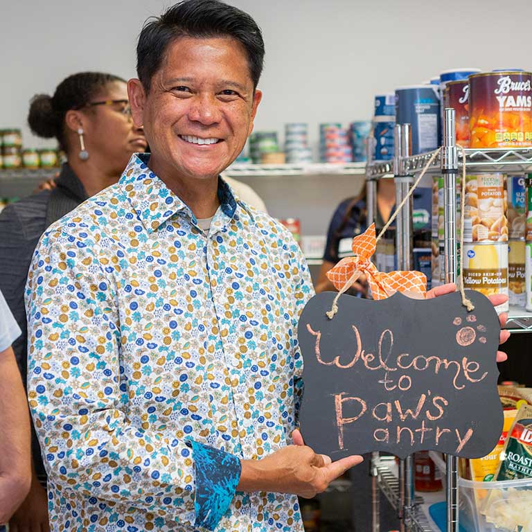 Merlin Gonzales with the 'Welcome to Paw's Pantry' sign.