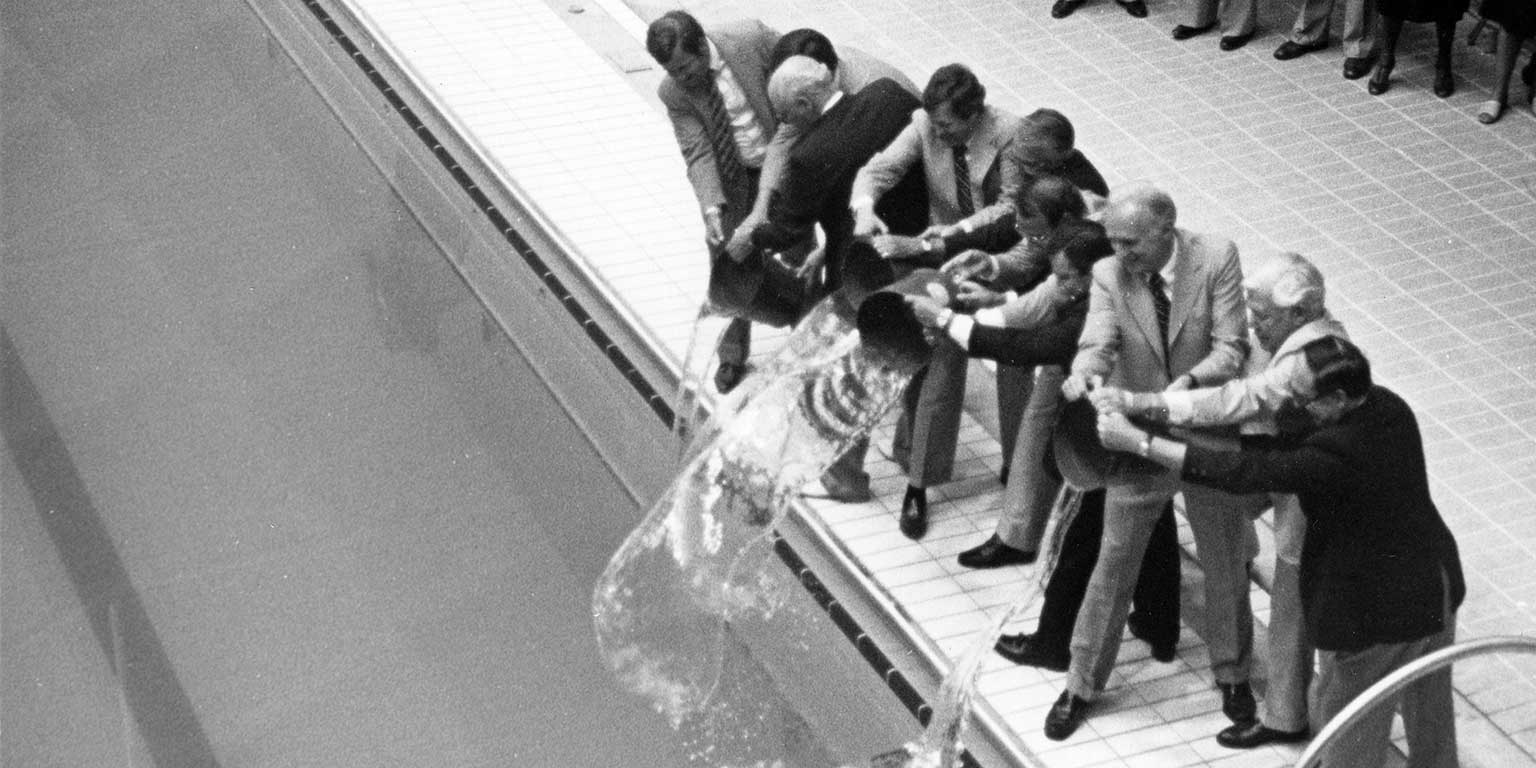 Several administrators dedicate the IU Natatorium by pouring buckets of water in it.