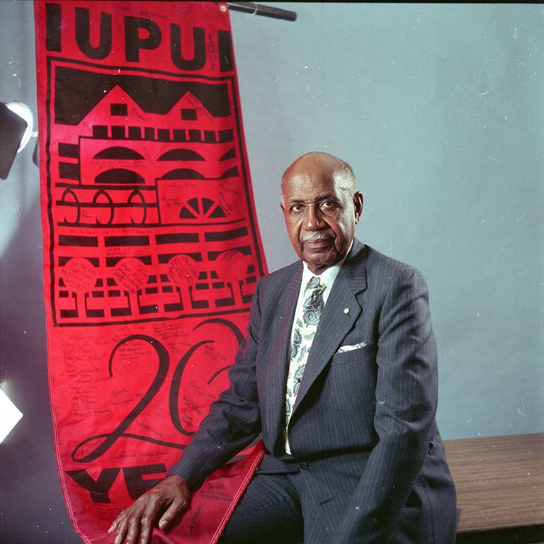 Joseph Taylor sits with a 20 years of IUPUI banner.
